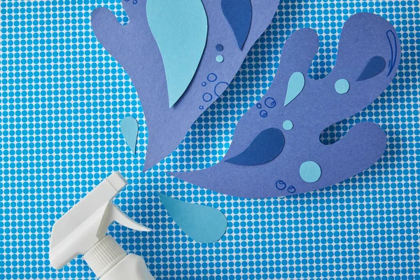 Spray bottle and blue water splashes made of paper, on blue — Stock Photo