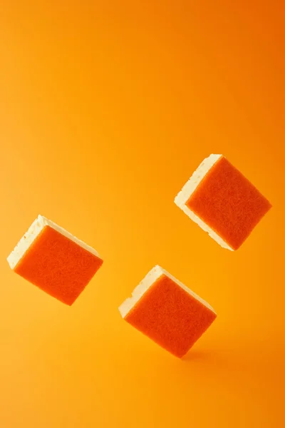 Falling sponges for dish washing on orange — Stock Photo
