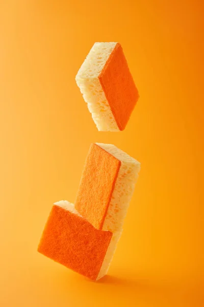 Falling sponges for dish washing on orange — Stock Photo