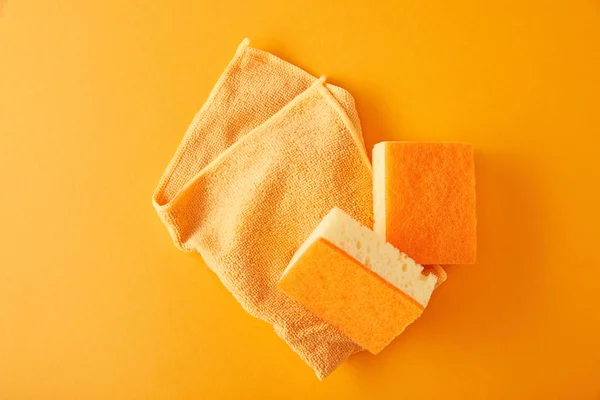 Вид зверху на ганчірку і жовті губки для прибирання будинку на апельсині — стокове фото