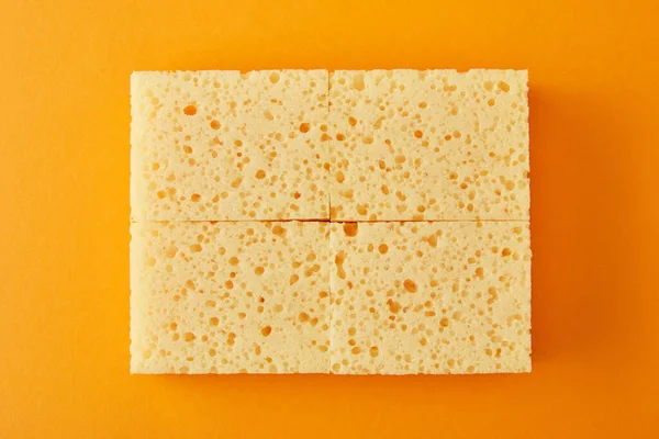 Top view of yellow sponges on orange — Stock Photo