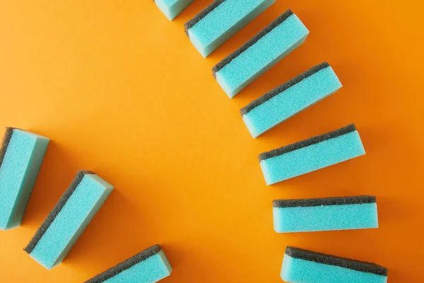 Vue de dessus des éponges bleues pour le nettoyage de la maison sur orange — Photo de stock