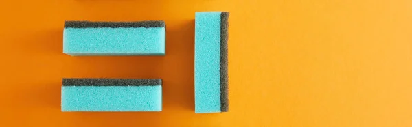 Panoramic shot of blue sponges for house cleaning on orange — Stock Photo