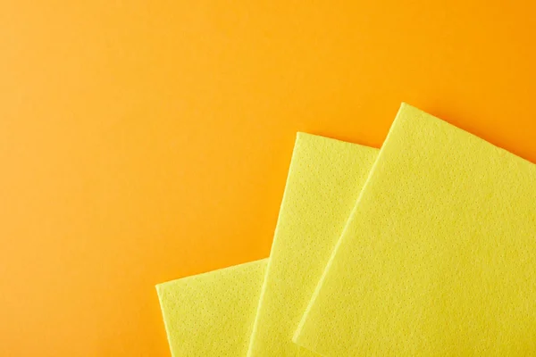 Вид сверху на желтые тряпки для уборки дома на оранжевом фоне с копировальным пространством — стоковое фото
