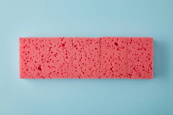 Vista dall'alto di fila di spugne rosa per la pulizia della casa su blu — Foto stock