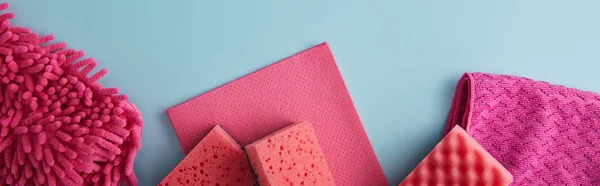 Panoramic shot of pink household goods for house cleaning on blue — Stock Photo