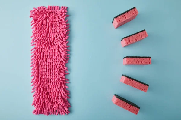 Deitado plano com pano rosa e esponjas para limpeza da casa em azul — Fotografia de Stock