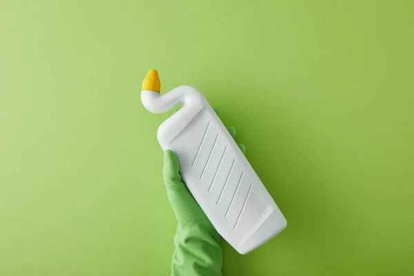 Top view of housekeeper in rubber glove holding bottle with toilet cleaner on green — Stock Photo