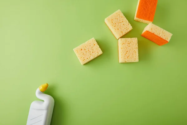 Vista superior de esponjas e garrafa com limpador de toalete em verde — Fotografia de Stock