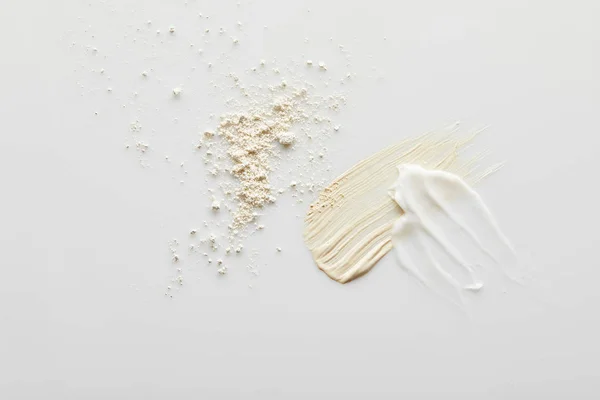 Top view of face powder, cosmetic and tone cream brushstrokes on grey background — Stock Photo