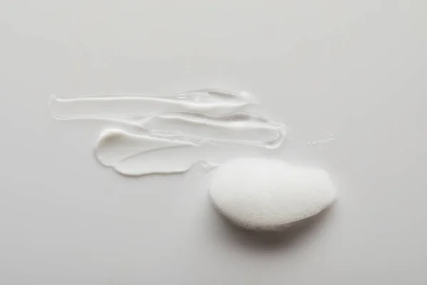 Vue du dessus des coups de pinceau gel et crème cosmétique près de la mousse de savon sur fond gris — Photo de stock