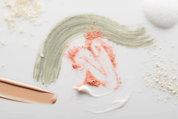 Draufsicht auf Kosmetik-, Toncreme- und Tonpinselstriche mit Blusher, Gesichtspuder, Meersalz und Seifenschaum auf Grau — Stockfoto