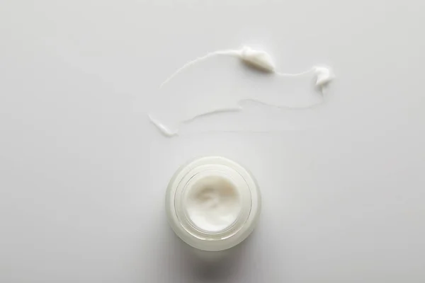 Vue du dessus du récipient avec crème cosmétique et coups de pinceau sur fond gris — Photo de stock