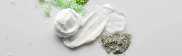 Draufsicht auf kosmetische Creme Pinselstriche, Gel, Tonpuder und Meersalz auf grauem Hintergrund, Panoramaaufnahme — Stockfoto