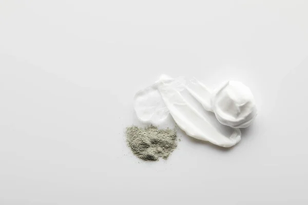 Vista dall'alto di pennellate crema cosmetica, gel, polvere di argilla su sfondo grigio — Foto stock