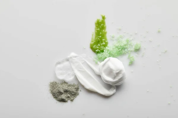 Draufsicht auf kosmetische Creme Pinselstriche, Gel, Tonpuder, Meersalz und Peeling auf grauem Hintergrund — Stockfoto