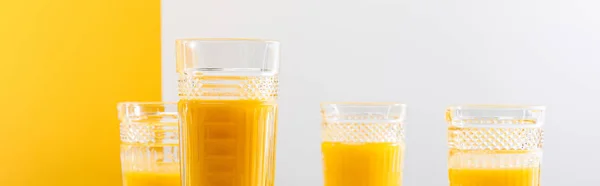 Glasses of fresh delicious yellow smoothie on grey and yellow background, panoramic shot — Stock Photo