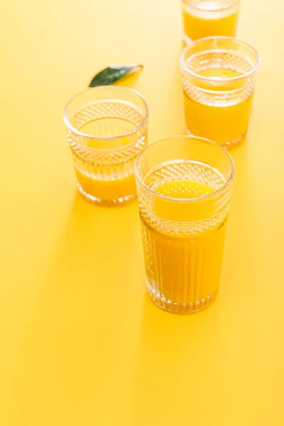 Foco seletivo de copos de smoothie amarelo delicioso fresco perto de folha verde — Fotografia de Stock