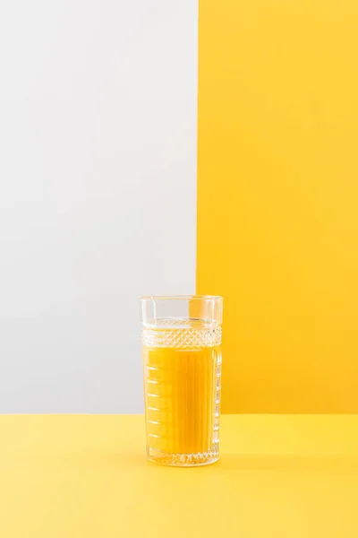 Glass of fresh delicious yellow smoothie on grey and yellow background — Stock Photo