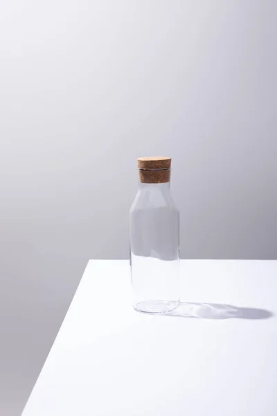 Empty glass bottle with cork on white surface isolated on grey — Stock Photo