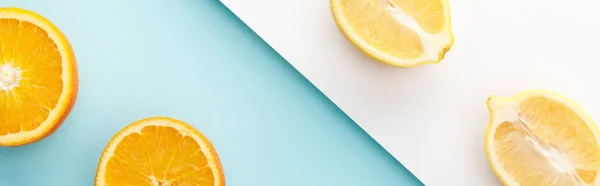 Вид зверху на оранжеві та лимонні половинки на синьо-білому тлі, панорамний знімок — стокове фото