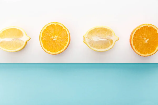 Top view of orange and lemon halves on blue and white background — Stock Photo