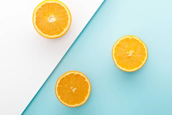 Vue de dessus des oranges moitiés sur fond blanc et bleu — Photo de stock