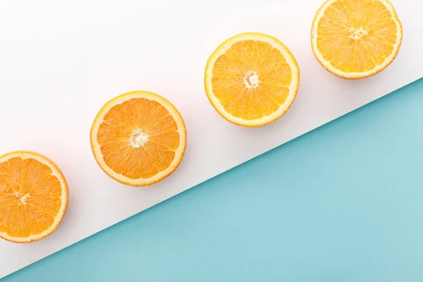 Vista superior de naranjas cortadas sobre fondo blanco y azul - foto de stock