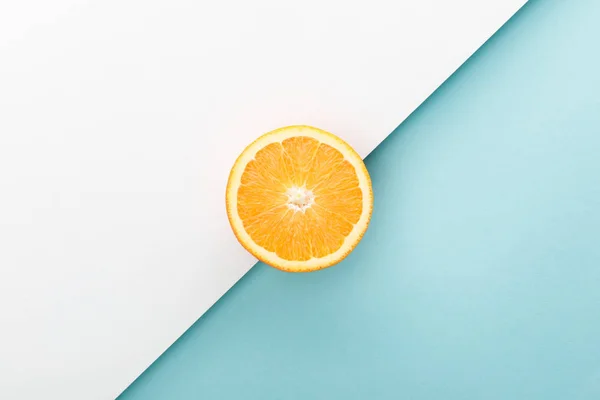 Top view of orange half on white and blue — Stock Photo