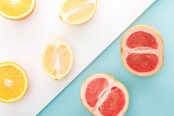 Vue de dessus des moitiés orange, citron, pamplemousse sur fond bleu et blanc — Photo de stock