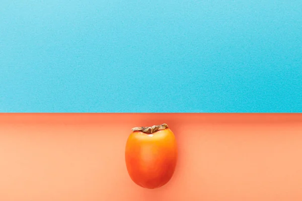 Верхний вид хурмы на голубом и оранжевом фоне — стоковое фото