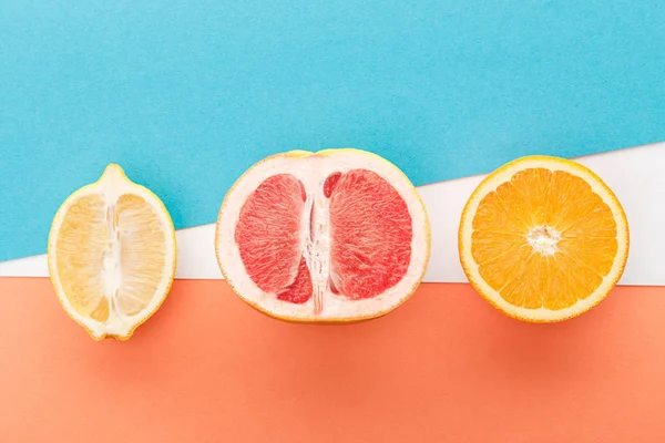 Vue de dessus des moitiés de fruits sur fond bleu, orange et blanc — Photo de stock