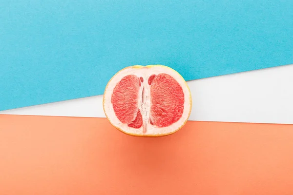 Вид сверху половинки грейпфрута на синем, оранжевом и белом фоне — стоковое фото
