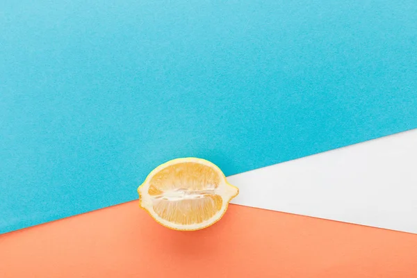 Вид зверху на половину лимона на синьому, помаранчевому та білому тлі — стокове фото