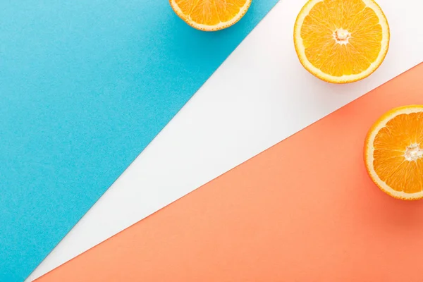 Vue de dessus des moitiés d'agrumes sur fond bleu, orange et blanc — Photo de stock