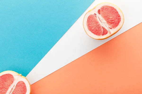 Draufsicht der Grapefruithälften auf blauem, orangefarbenem und weißem Hintergrund — Stockfoto