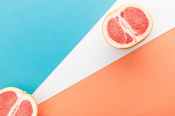 Vista superior das metades de toranja sobre fundo azul, laranja e branco — Fotografia de Stock