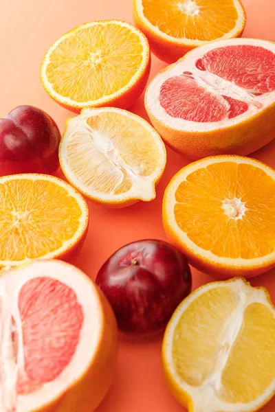 Enfoque selectivo de las mitades de cítricos y manzanas sobre fondo naranja - foto de stock