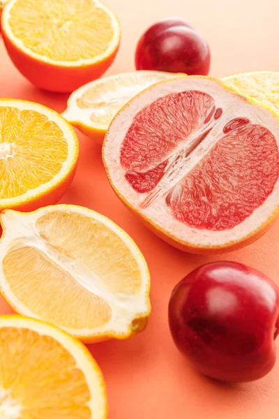 Mitades de cítricos y manzanas sobre fondo naranja - foto de stock