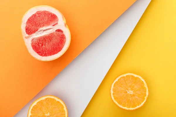 Vue de dessus des moitiés d'agrumes sur fond jaune, orange et blanc — Photo de stock