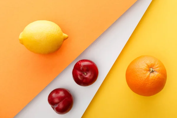 Top view of citrus fruits and apples on yellow, orange and white background — Stock Photo