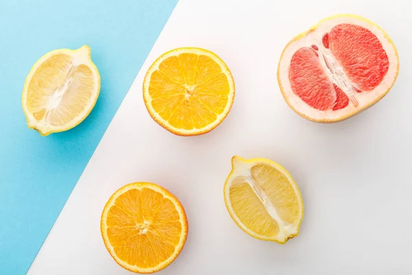 Top view of citrus halves on white and blue background — Stock Photo