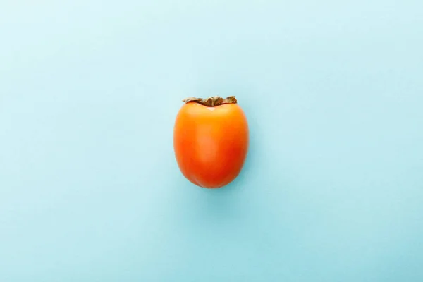 Top view of persimmon on blue background — Stock Photo