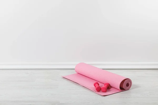 Alfombra de fitness rosa y mancuernas en el suelo - foto de stock