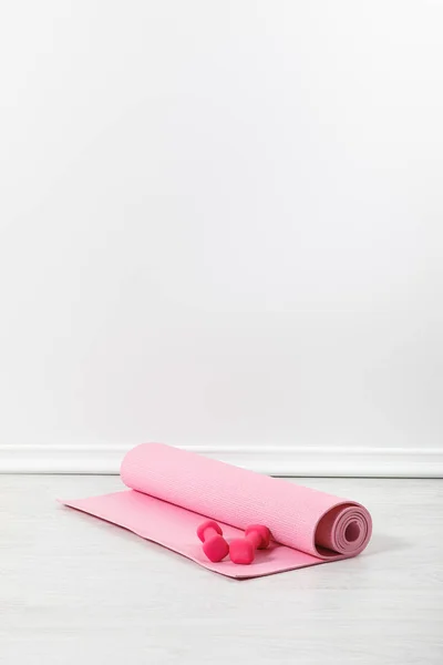 Tapete de fitness rosa e halteres no chão — Fotografia de Stock