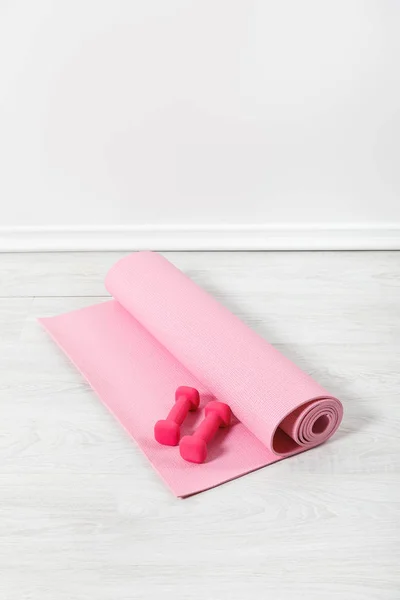 Alfombra de fitness rosa y mancuernas en el suelo blanco - foto de stock