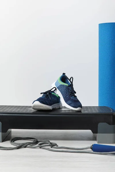 Plataforma passo, tapete de fitness azul, pulando corda e tênis no chão em casa — Fotografia de Stock