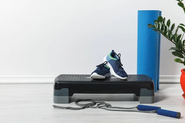 Plataforma passo, tapete de fitness azul, pulando corda e tênis em casa — Fotografia de Stock