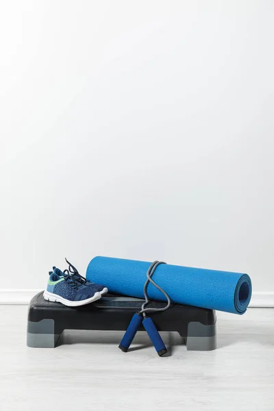 Plataforma paso, colchoneta de fitness, saltar la cuerda y zapatillas de deporte en casa - foto de stock