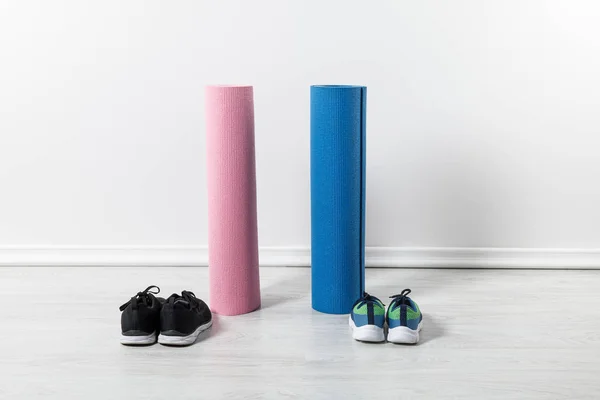 Sapatilhas e tapetes de fitness no chão em casa — Fotografia de Stock